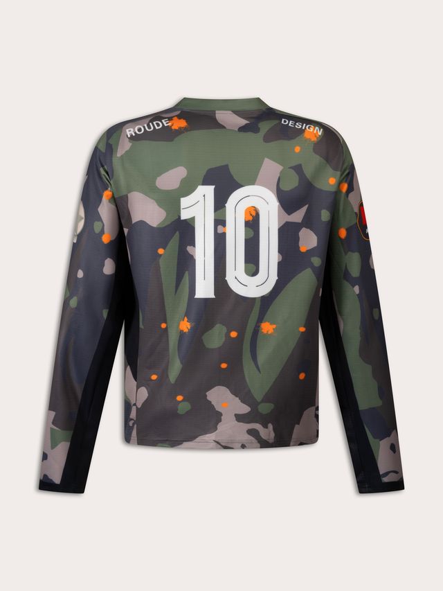 Alliant style streetwear et inspiration sportive, ce maillot se distingue par son imprimé camouflage revisité avec des touches de couleurs vives. À l’avant, le logo ROUDE s’impose au centre, accompagné de patchs et détails graphiques qui renforcent l’esprit football vintage. Au dos, le numéro 10 apporte une finition iconique, clin d’œil aux légendes du terrain.

Confectionné dans une matière légère et respirante,.  Sa coupe ample et fluide garantit confort et liberté de mouvement.

